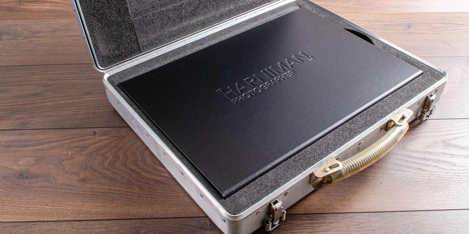 Professional photographers personalised portfolio box with blind embossed logo stamped into the cover. The box is placed in photographers case