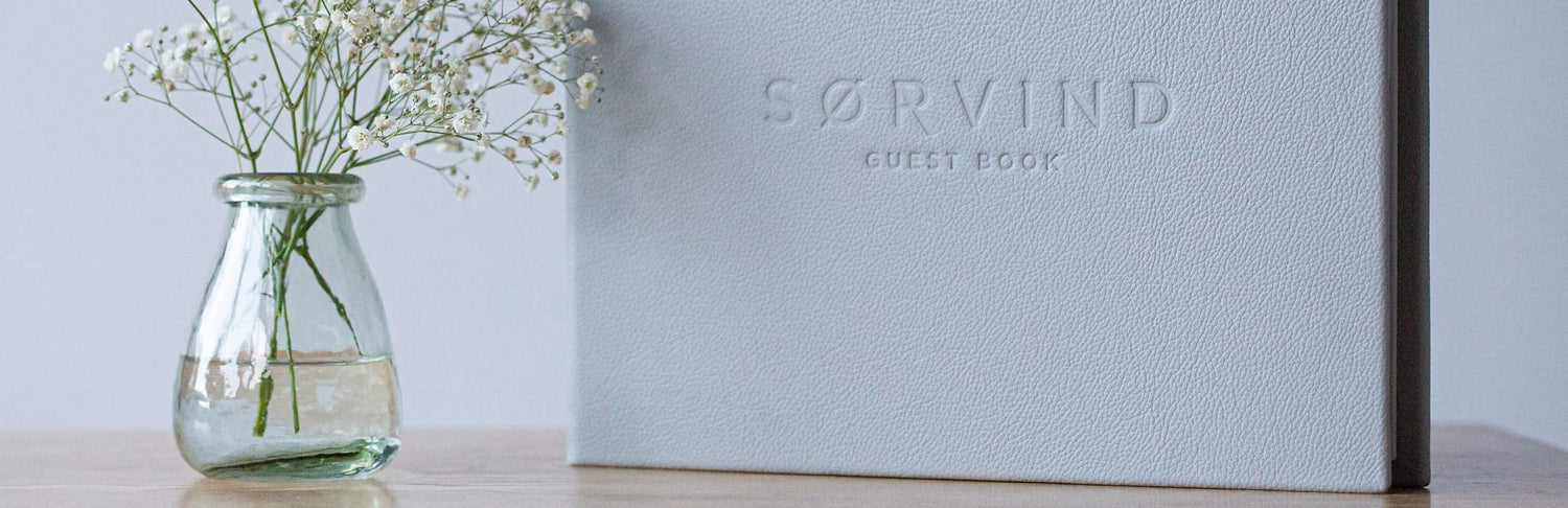 Leather bound guest book next to flowers with embossed personalised cover