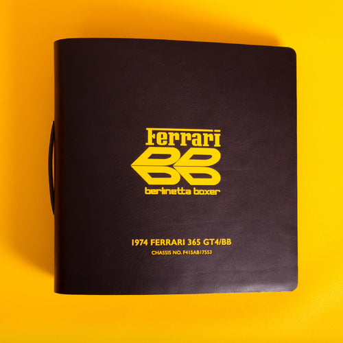 Black leather binder with yellow Ferrari and BB and text on a for car history documents