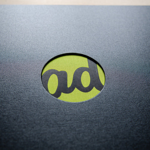 black foil logo on green fabric behind circular cut out for luxury design portfolio book
