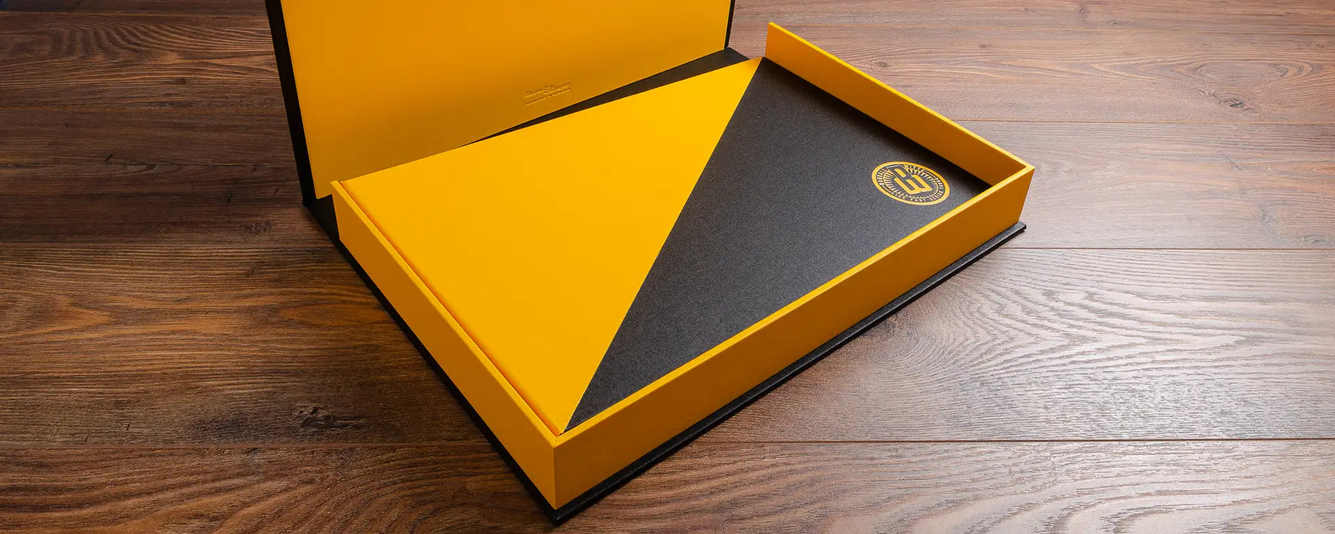 yellow 11x17 clamshell box with a yellow and black portfolio book inside that has a logo printed on the cover