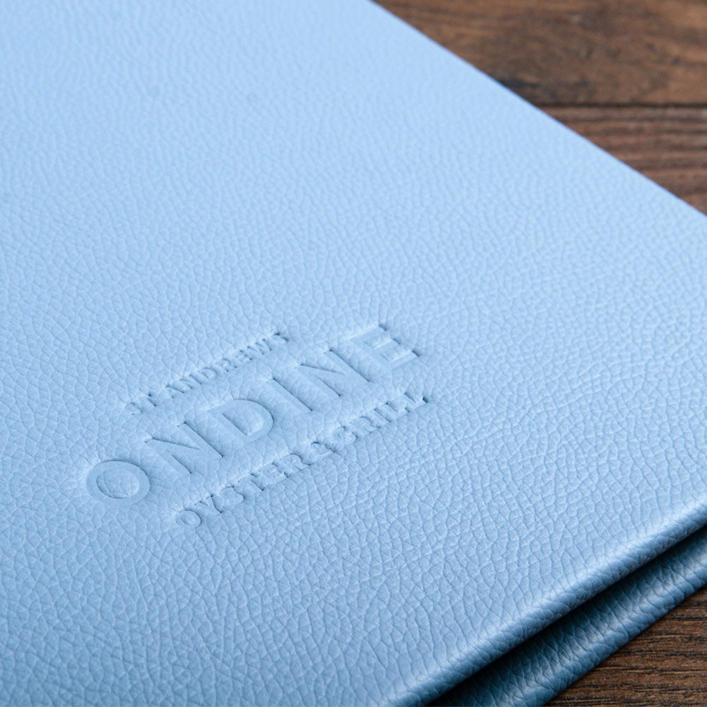 blind debossed restaurant logo etched into the light blue leather of a menu cover - Gallery image 3