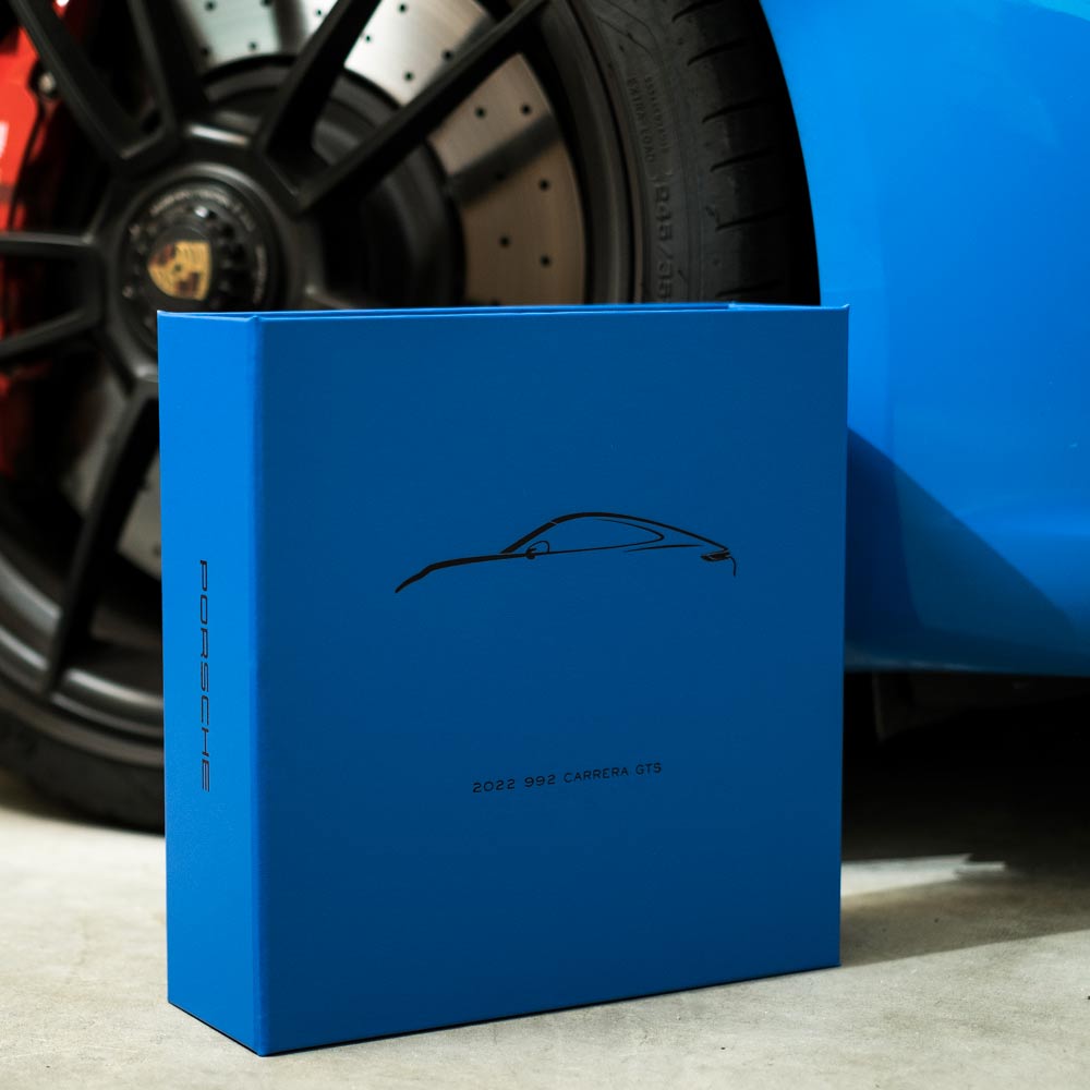 blue personalised car history file with porsche personalisation with 911 car wheel in the background - Gallery image 1