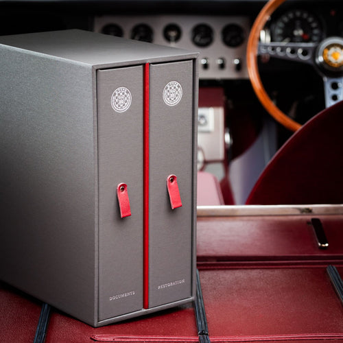 grey box containing two luxury ring binders, also grey but with red tags. the boxes have the E type jaguar badge and the words documents and restoration