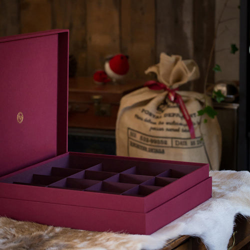 luxury red Christmas decoration box with sixteen sections by Hartnack and co. in the background there is a brown sack