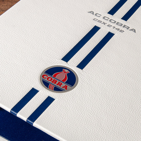 Custom made AC Cobra history file in white leather with blue stripes and etched cobra badge inset into the cover