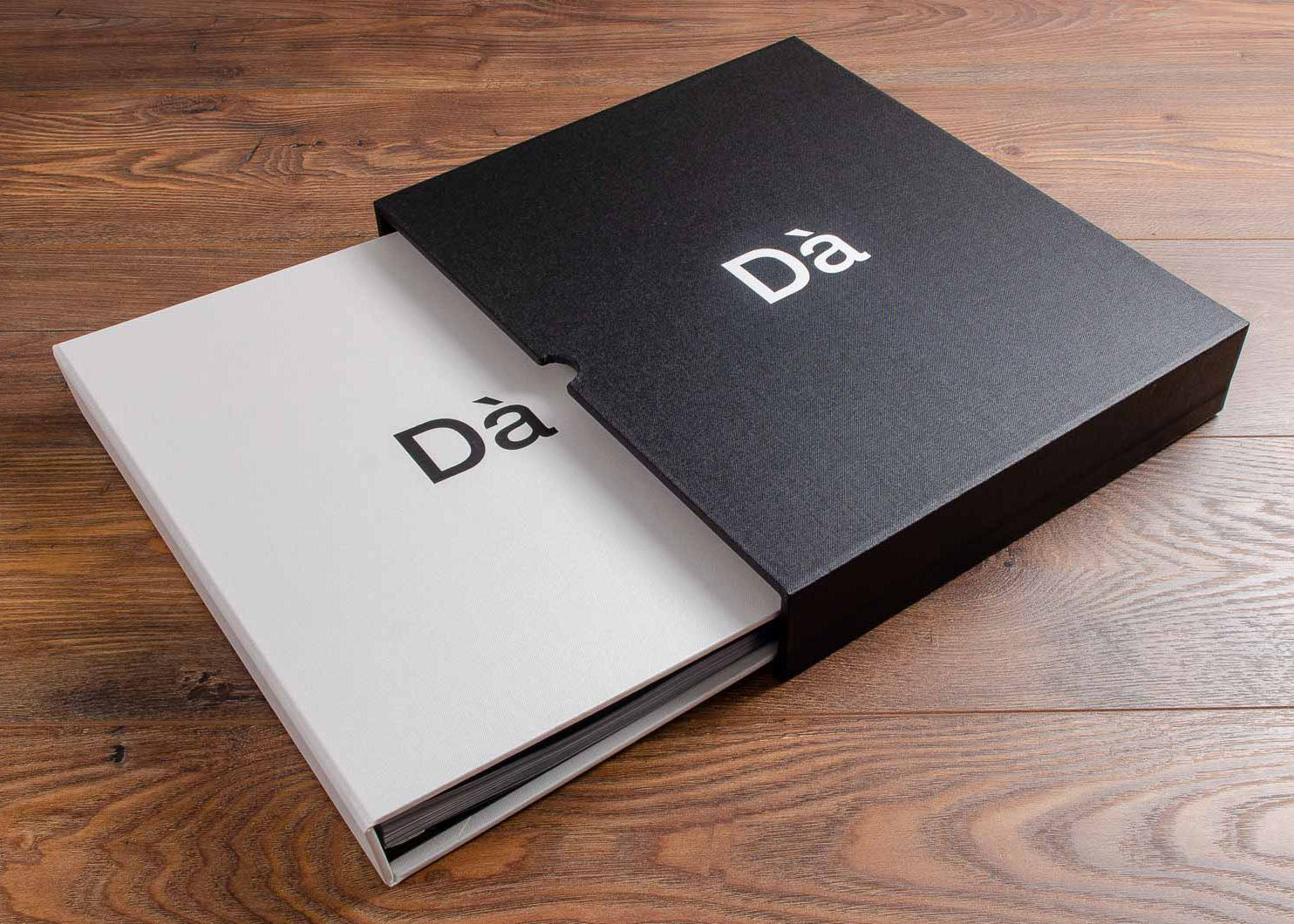 Photography portfolio book and slipcase. Size - A4, Product - case bound screw post binder with black foil stamping, Fabric - white buckram. A4 Slipcase in black buckram with optional finger notches and white foil personalisation