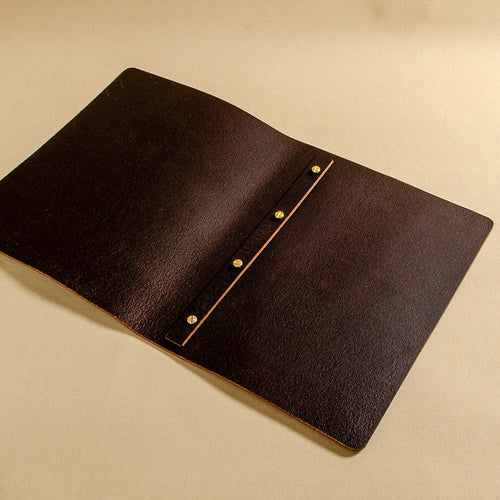 Dark brown leather screw post menu cover with a vertical leather strap and four gold-tone screw post caps laying open