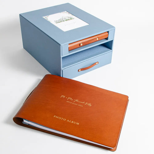 Brown leather personalised wedding photo album with gold foil embossing in front of blue leather storage keepsake box