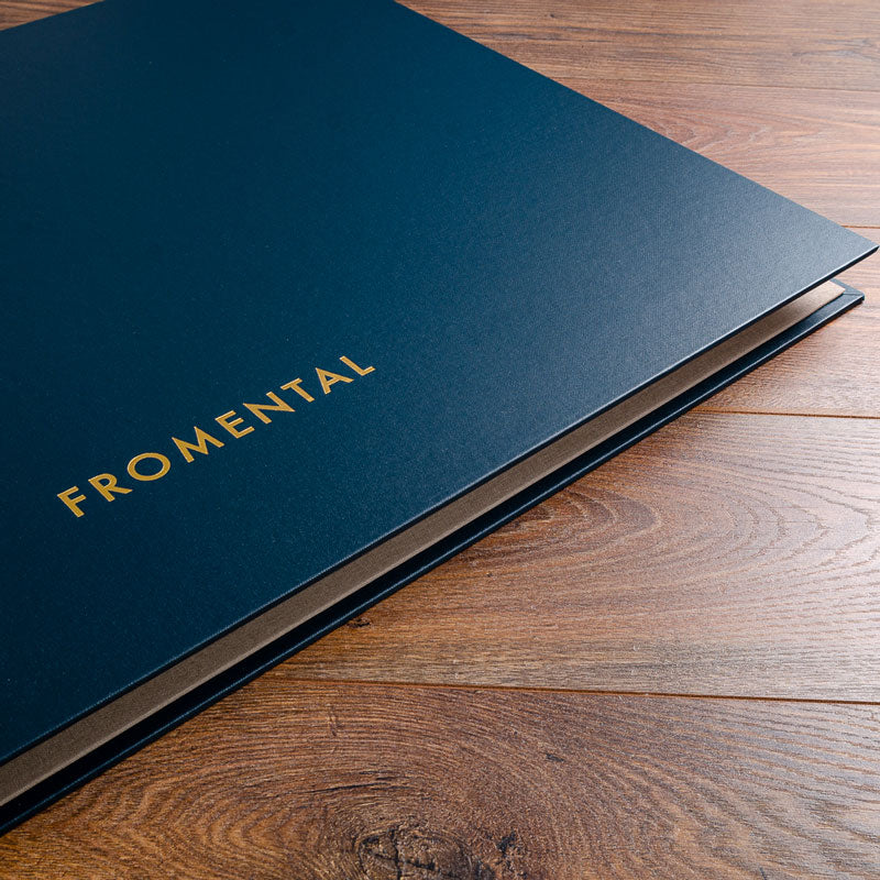 Blue fabric swatch book binder on wooden floor with gold foil logo embossed on the cover - Business, Casebound Binders, Photographers & Designers, All Screw Post Binders