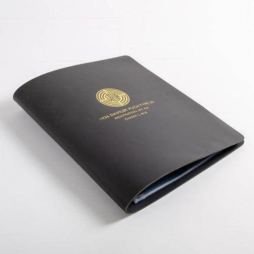 Dark grey leather binder for car documents with text and a logo embossed in gold on the cover