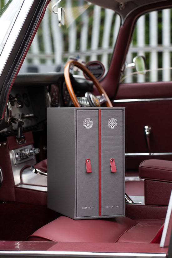 custom car document and history binder in grey and red sitting on the seat of a a car.