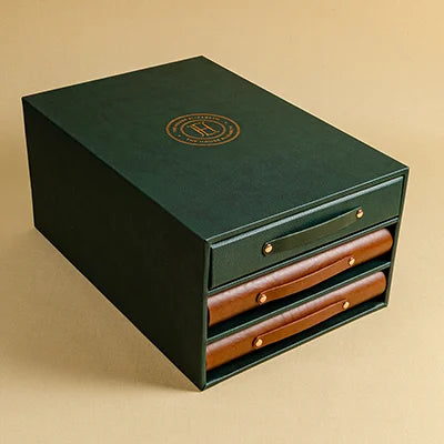 Dark green vegan leather slipcase with 2 brown leather binders and 1 faux green binders. The box has been personalised with a copper foil embossing