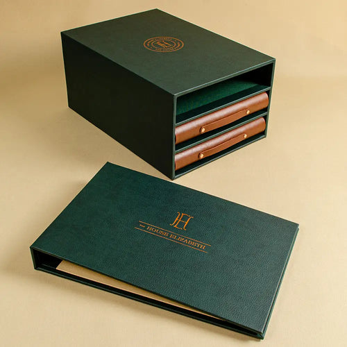 Dark green A4 luxury personalised leatherette ring binder with a foil embossed cover set behind a slipcase with two brown leather ring binders 