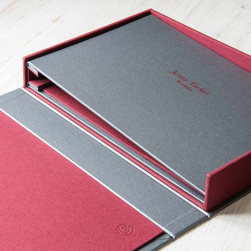 silver buckram screw post binder with red personalised cover sitting in clamshell box
