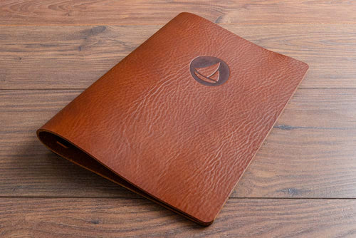 Brown saddle hide leather menu cover with a personalised embossed logo on a wooden surface