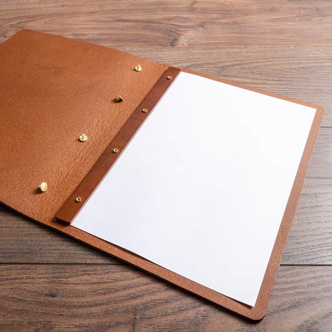 Brown leather menu cover with screw posts and a white page on a wooden surface - Gallery image 4