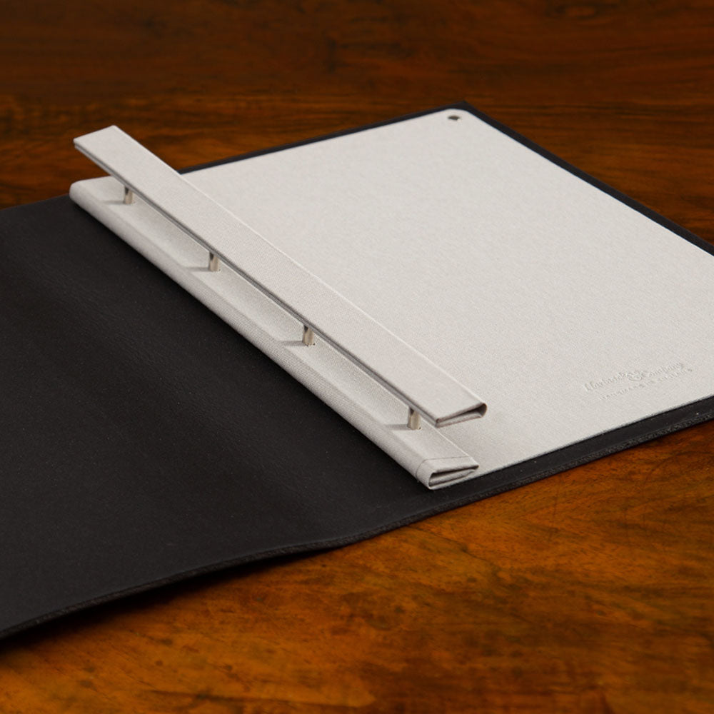 Custom made leather screw post portfolio book lying open with binder showing