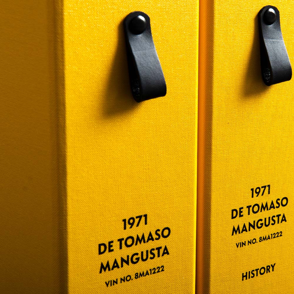 Close-up of yellow file spine with black leather pull tags and personalised details of De Tomaso classic car - Gallery image 5