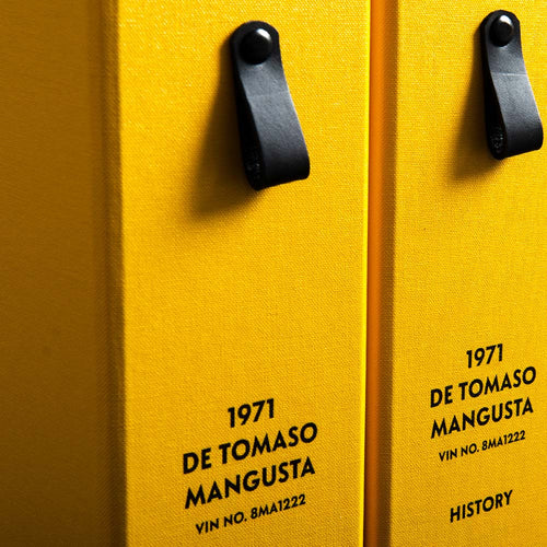 Close-up of yellow file spine with black leather pull tags and personalised details of De Tomaso classic car