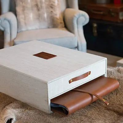 fabric covered keepsake box with a personalized embossed plaque and a drawer and leather folder sitting on a deer skin rug