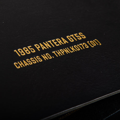 Gold foil text on a black leather binder personalised with '1985 Pantera GT55' and the Chassis Number embossed into the cover. 