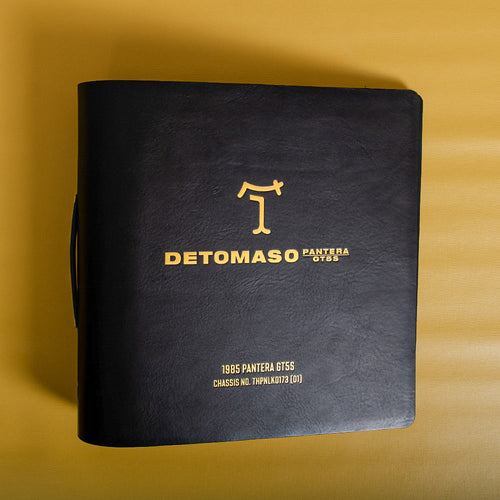 Black leather ring binder with gold foil text and logo on a yellow background