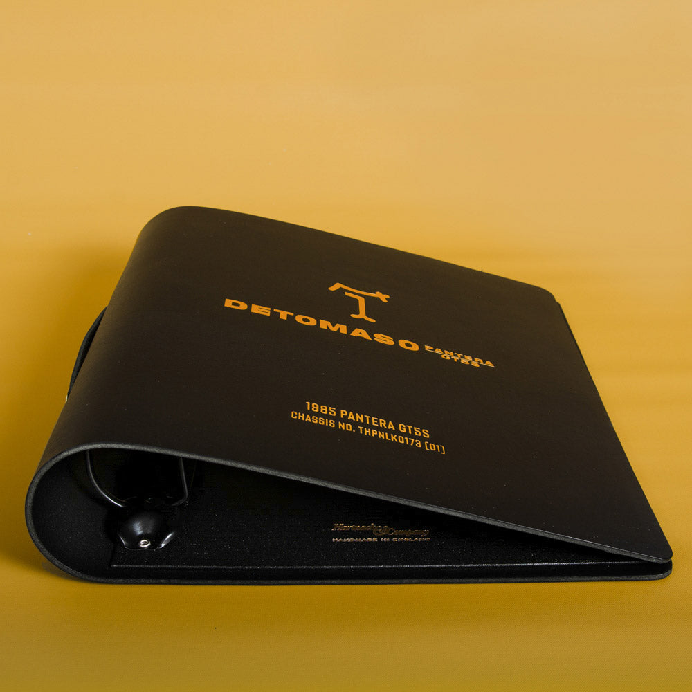 Black leather car document holder with Detomaso Pantera GT5S branding with car details on a yellow background - Gallery image 5