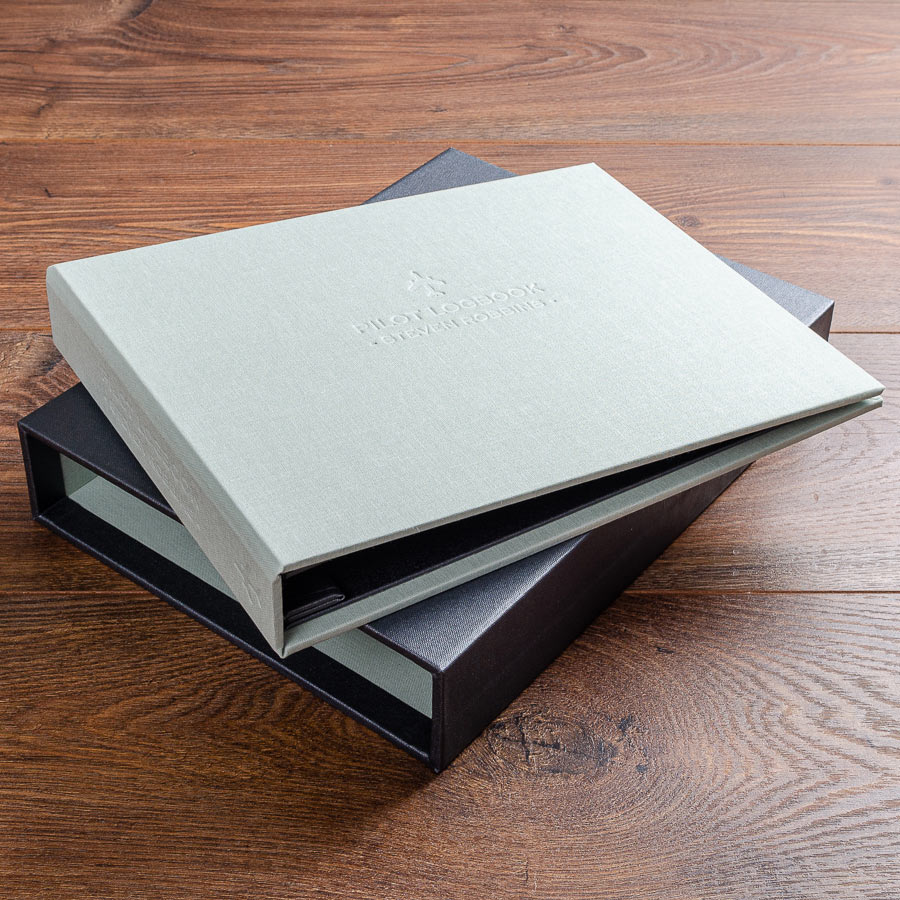 personalised pilot logbook binder in green book cloth with blind embossed  cover and spine sitting on grey slipcase cover - Gallery image 4