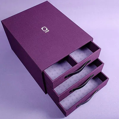 custom made presentation box in purple with three drawers with printed lining and personalised with a white logo foiled on the cover 
