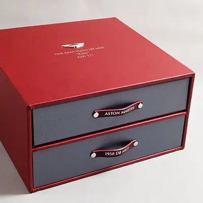Luxury red leather bound box with Aston Martin badge in laid on the top with silver foil embossed titles of 1958 B5 on the top. The box a vehicle history file and drawer for documents