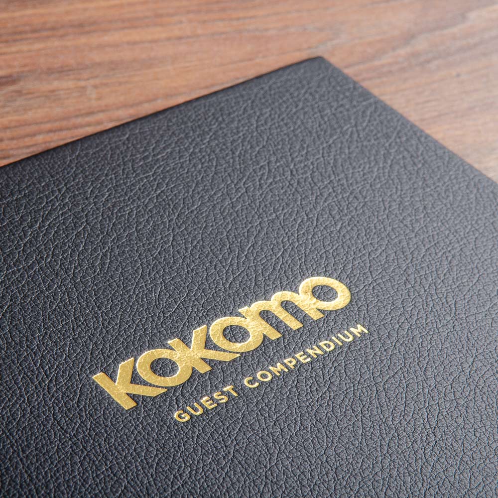 gold foil embossing on the cover of a black leather binder with the name of a superyacht on and a title 'guest compendium' - Gallery image 6