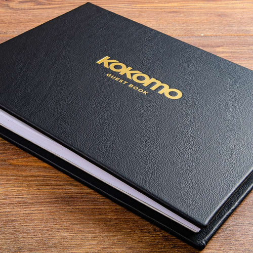 black leather guest book with a logo gold foiled on the cover and the words 'guest book' printed on the cover