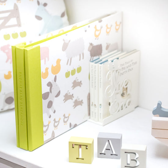 custom made baby album with printed animals on the cover a green spine with a personalised name embossed on it