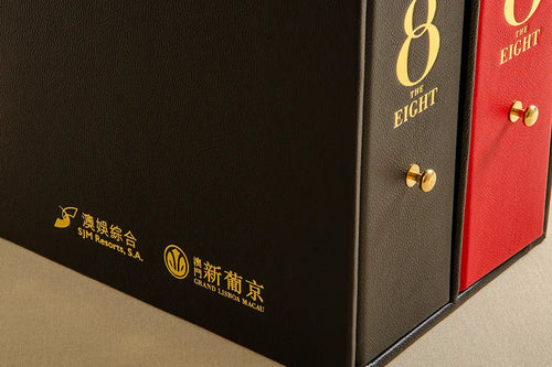 Close up of gold foil embossed leather slipcase with two leather ring binders also gold foiled with brass pulls on the spine of the ring binders. 