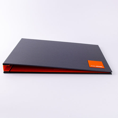 Photographers presentation portfolio book in black buckram with orange personalised plaque custom made by Hartnack and Co