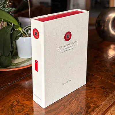 White leather bound personalised luxury box file with silver foil embossed cover and spine and round metal disk inserts of Jaguar XK150 for car documents