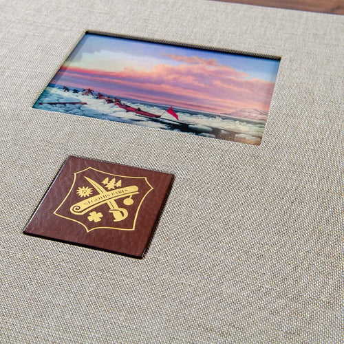 close up of personalised clamshell box with window in the cover for a picture and brown leather plaque with a logo gold foiled onto it