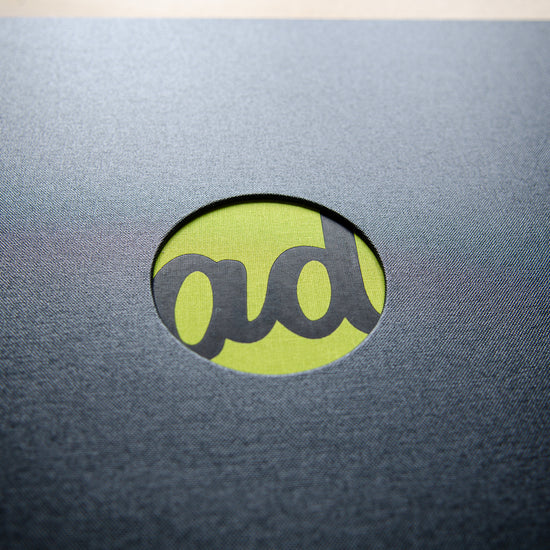 close up photo of a black foiled logo with a circular cut out in the cover of custom made high quality portfolio book by Hartnack and Co