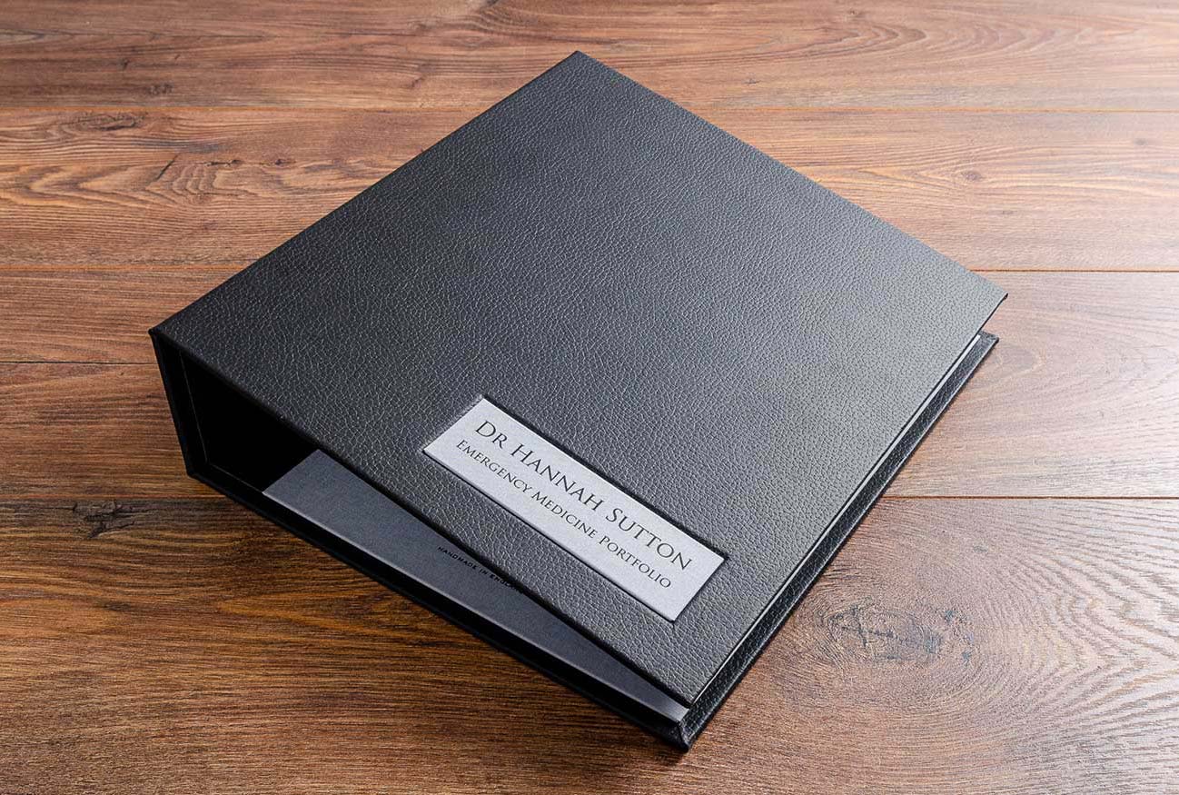 Emergency medicine medical portfolio in black faux leather with a name plaque matching the inner cover fabric and the name embossed in black foil
