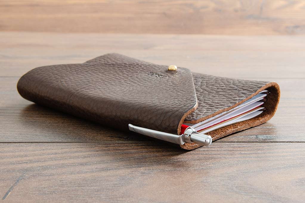 Leather Notebook Cover Closed Holding Three Field Note Book and Ball Point Pen