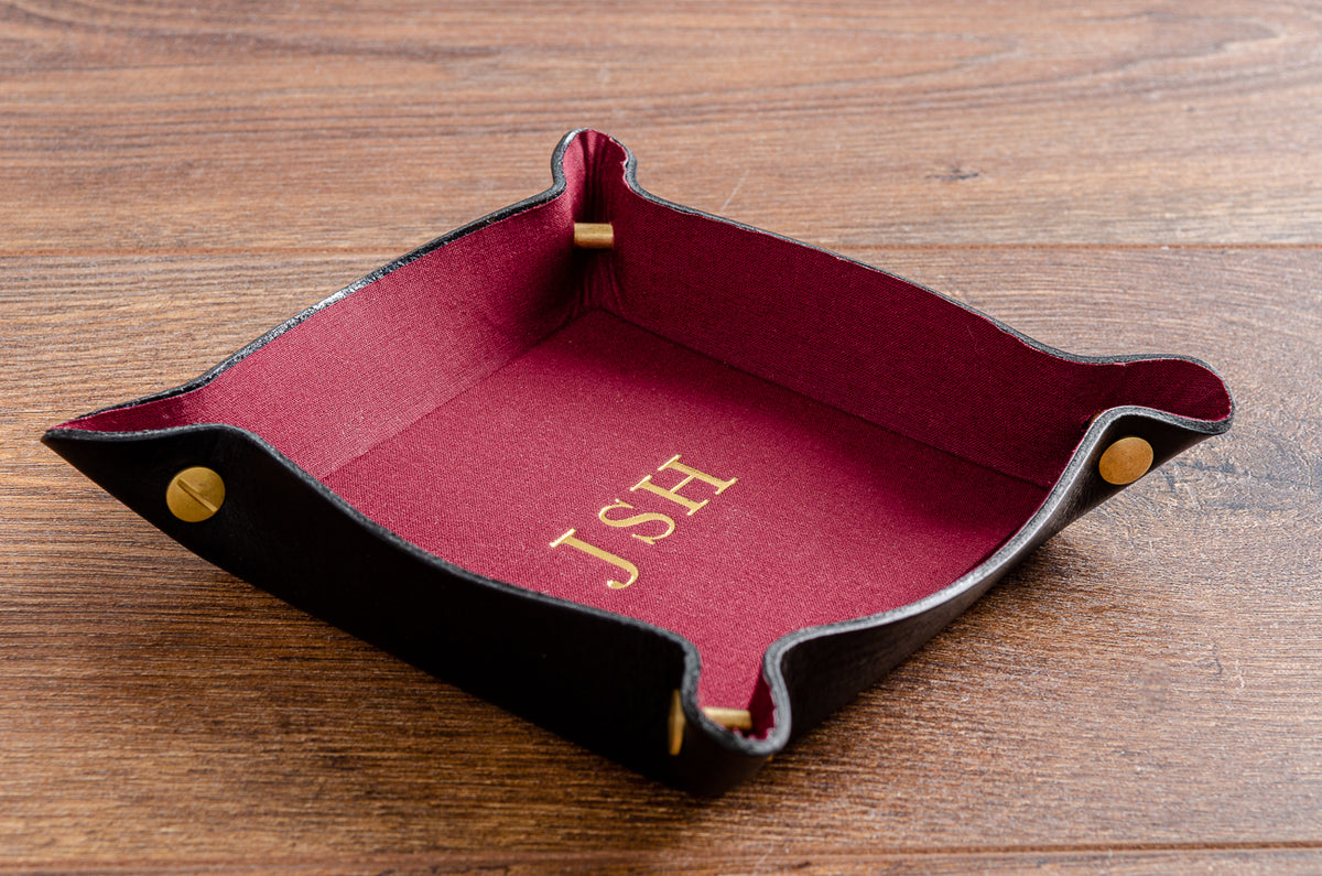 Leather valet tray personalised with gold foil embossing, in black veg tanned leather with red fabric lining. 100mm x 100mm