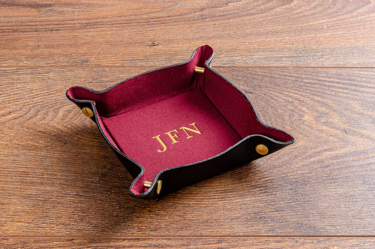 Personalised leather valet tray for coins and keys, with red fabric lining and gold foil embossing. 80mm x 80mm